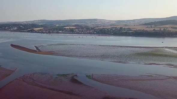 Drone flying in a clear sky towards the coastal town of Lympstone England. Agricultural lands and fi alt