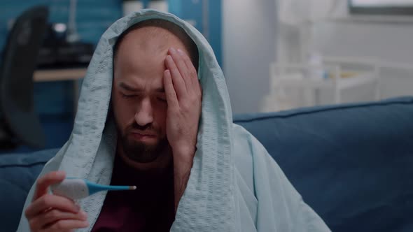 Close Up of Man Wrapped in Blanket with Thermometer alt