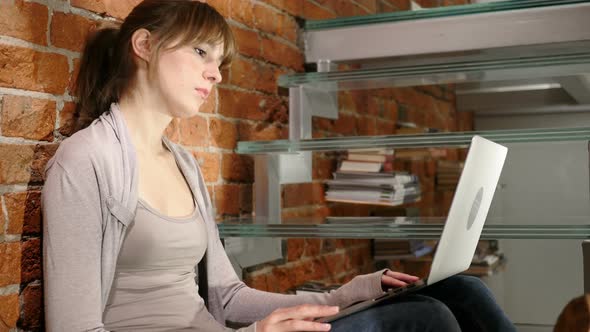 Young Woman Upset by Loss while Working on Laptop alt