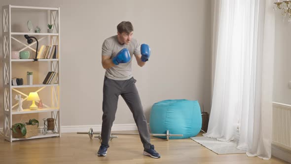 Wide Shot of Confident Handsome Male Boxer in Boxing Gloves Fighting Shadow alt
