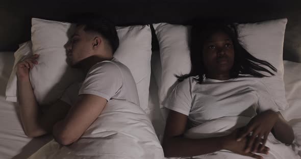 Young Multi-ethnic Couple in the Bed Laying Unhappy After a Quarrel. Night Time. alt