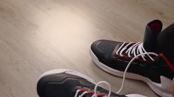 Closeup of a Man Wearing a Black Sock Basketball Sneaker on His Foot and Tying His Shoelace alt