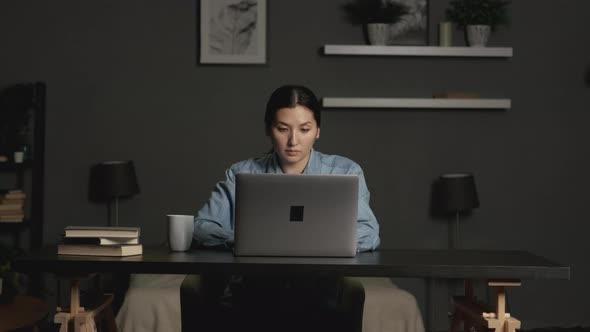 Thoughtful concerned asian woman working on laptop computer at home office, serious woman  alt