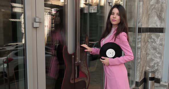 Gorgeous girl in pink near the music store with a disc alt