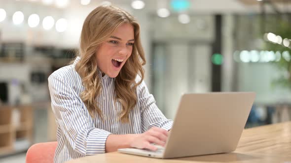 Excited Businesswoman Celebrating Success on Laptop in Office  alt