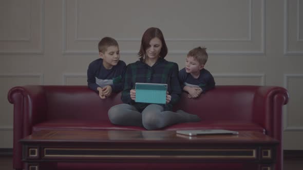 Family of single mother and two boys using tablet computer on couch  alt