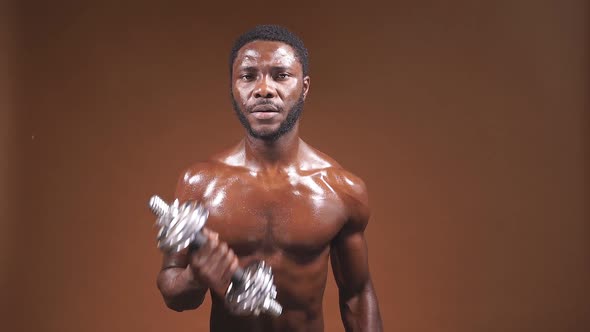 Closeup of an African Athlete with a Bare Chest and a Dumbbell in His Hands Isolated Background