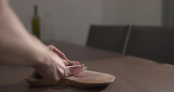 Slow Motion Man Slicing Salame on Olive Wood Board on Walnut Table alt