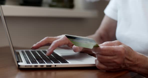 Senior Woman's hands Typing on Laptop and Holding Credit Card