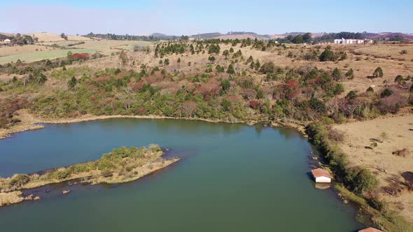 Scenic lake with dry forest trees at edge of lake at end of winter alt