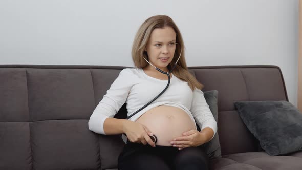 A Pregnant Woman Listens to the Movements and Heartbeat of the Fetus with a Stethoscope alt