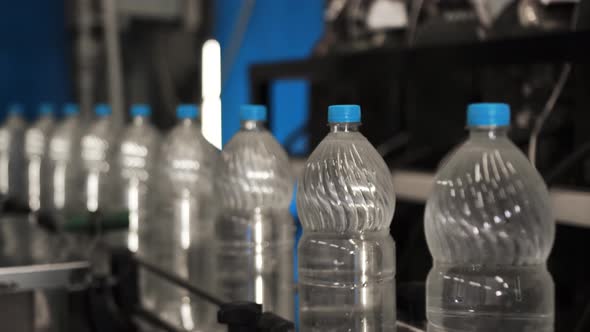 Plastic Bottles with Water Ride One After Another in a Row on a Conveyor Belt