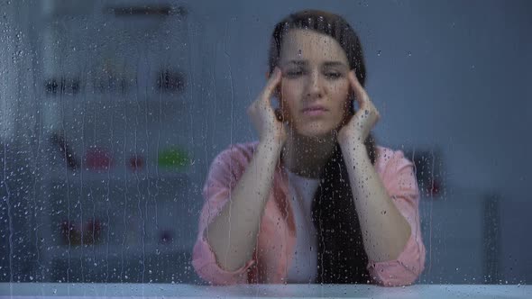 Exhausted Woman Suffering From Head Ache Behind Rainy Window, Migraine Disorder alt