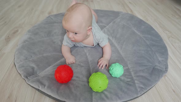 Cute Baby Lying on His Tummy on Play Mat 3 Month Old Newborn Infant Boy Playing with Colorful alt