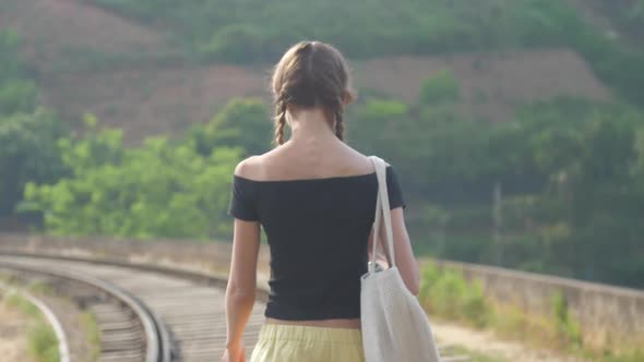 Tourist Walks Along Railroad on Famous Bridge Against Hills alt