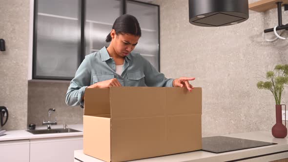 Disappointed Young African American Girl Standing at the Kitchen with Carton Box and Feeling Upset alt