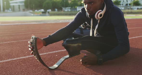 Disabled mixed race man with prosthetic legs stretching before a race alt