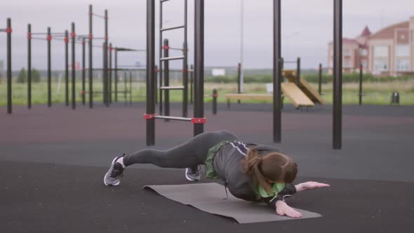 Athletic Woman Performing Side Plank Reverse Fly during Outdoor Workout alt