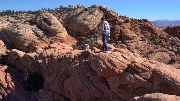 Woman hiking over rocky desert terrain in the desert alt