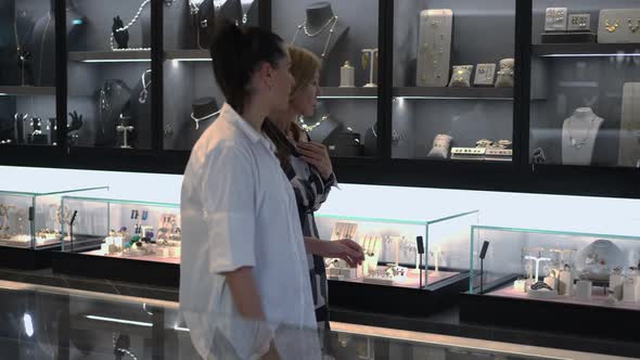 Two Women Walking Along Shelves in Luxurious Jewellery Store Talking in Slow Motion alt