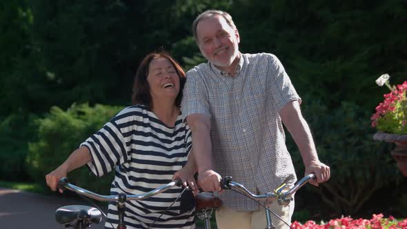 Happy Senior Couple with Bikes Having Fun at City Park alt
