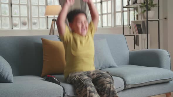 Child Gamer Sitting On A Couch, Playing And Winning Games On A Console alt