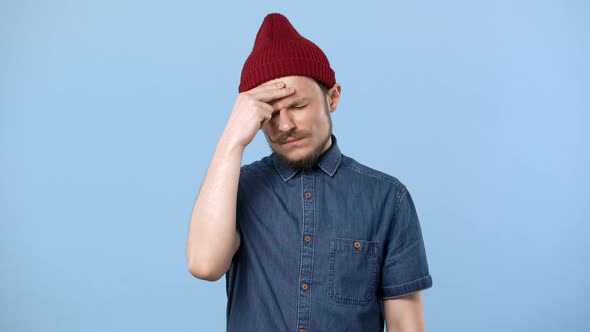 Portrait of Sick Guy 20s Wearing Hat Rubbing Temples Due to Headache and Suffering From Migraine alt