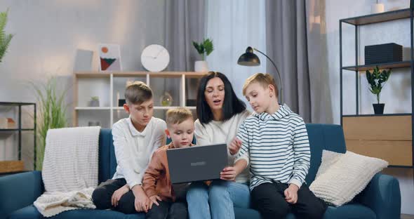 Mother Explaining How to Use Laptop Her three Interested Different Ages Sons alt
