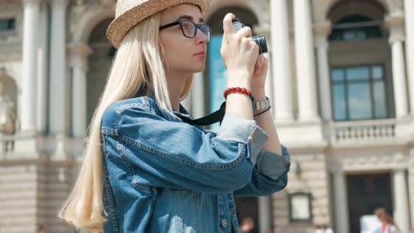 Young woman tourist taking a picture on retro camera of a city on vacation