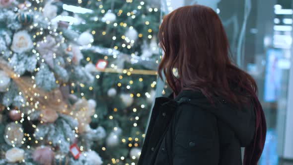 A Young Beautiful Woman Walks Around the Store and Selects Christmas Decorations and Decorations to alt