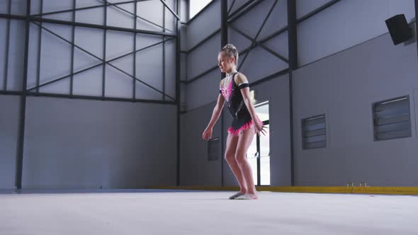 Teenage female gymnast performing at sports hall alt