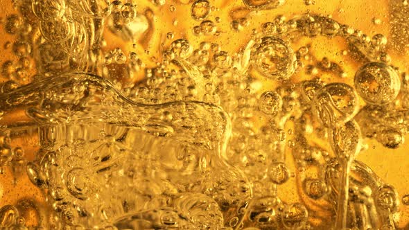 Super Slow Motion Shot of Moving Oil Bubbles in Water on Golden Background at 1000Fps. alt