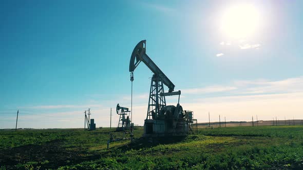 Green Field with Pumpjacks Extracting Oil. Crude Oil, Gas, Petroleum Prices Concept. alt
