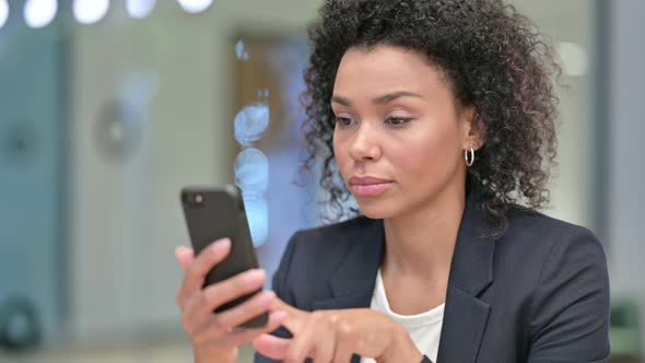 African Businesswoman Celebrating Success on Smartphone alt