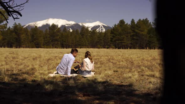 Young Couple Watching Wedding Photos in Nature with Scenic View