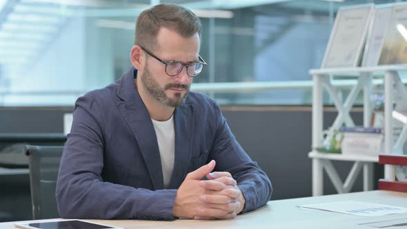 Middle Aged Businessman Thinking While Sitting in Office alt