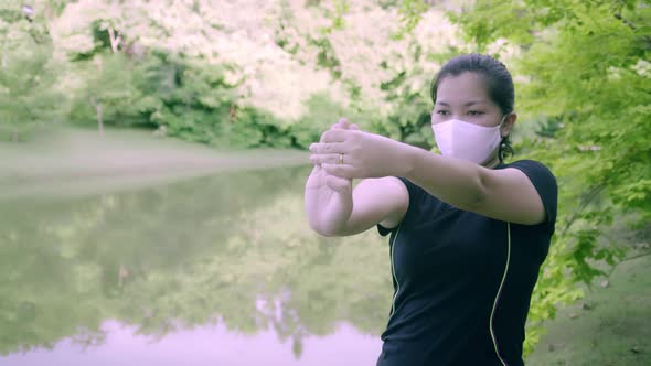 Asian woman exercise in park outdoor with new normal in COVID-19 situation alt