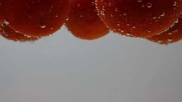 Close up of Tomatoes floating in water. Static. Slomo. Low POV alt