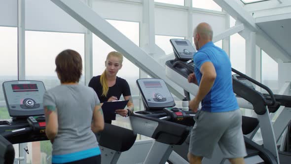 Trainer Talking to Man and Woman in Gym alt