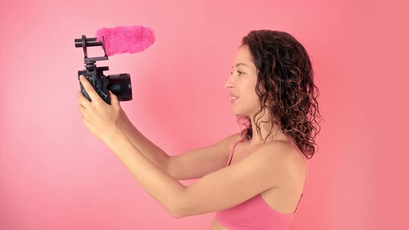 Young Woman Vlogger Recording Broadcast in Slow Motion on a Pink Background alt