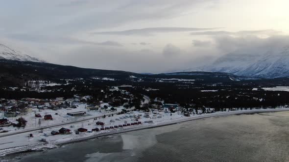 Flying over a small village and Lyngenfjord in Lyngen Alps, Norway, Arctic alt