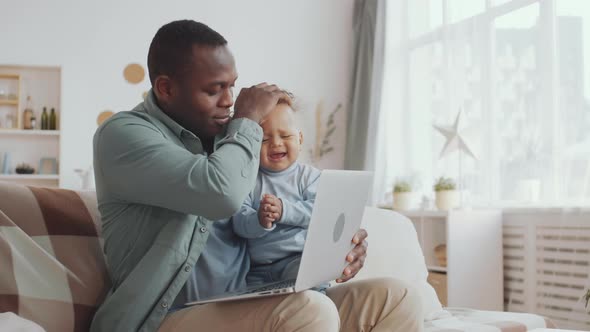 Man Using Laptop while Babysitting alt