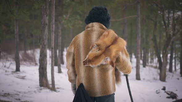 Live Camera Follows Old Asian Male Hunter Walking in Woods in Slow Motion on Winter Day alt