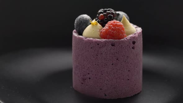Mousse dessert with fresh berries rotating on black background