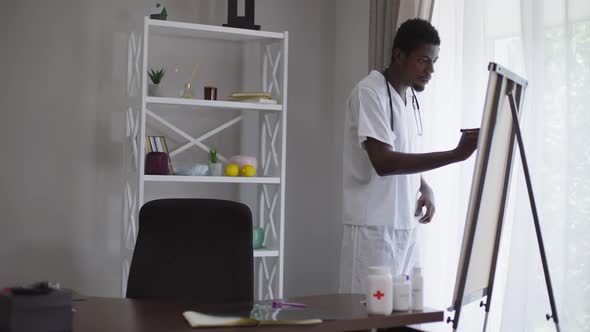 Concentrated Smart African American Doctor Standing at Flipchart Writing and Thinking alt