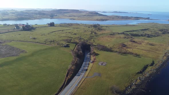 Subsea byfjord tunnel in Stavanger Norway - Aerial approaching and decending towards entrance in sun alt
