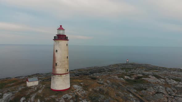 Aerial approach and rotation by a drone around a historic bricklight lighthouse in Norway has the su alt