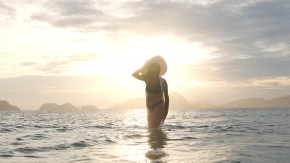 Woman In Thong In Sea Facing Glowing Sunset alt