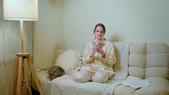 Woman musician with money in us dollars at home on sofa in living room