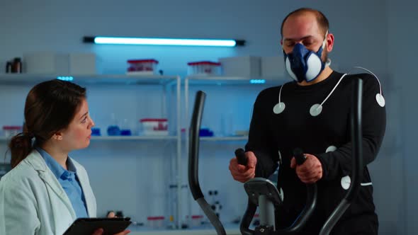 Doctor Science Typing on Tablet While Measuring Sportsman Endurance alt